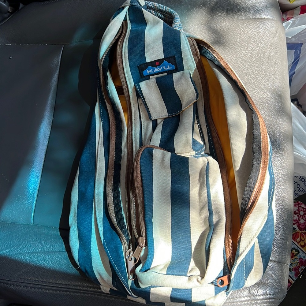 A blue tan and white kavu sling backpack